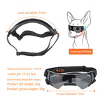 Black dog goggles with adjustable head strap and tinted lenses, shown with measurement annotations, a lens curvature note, and a line drawing of a dog wearing the product.